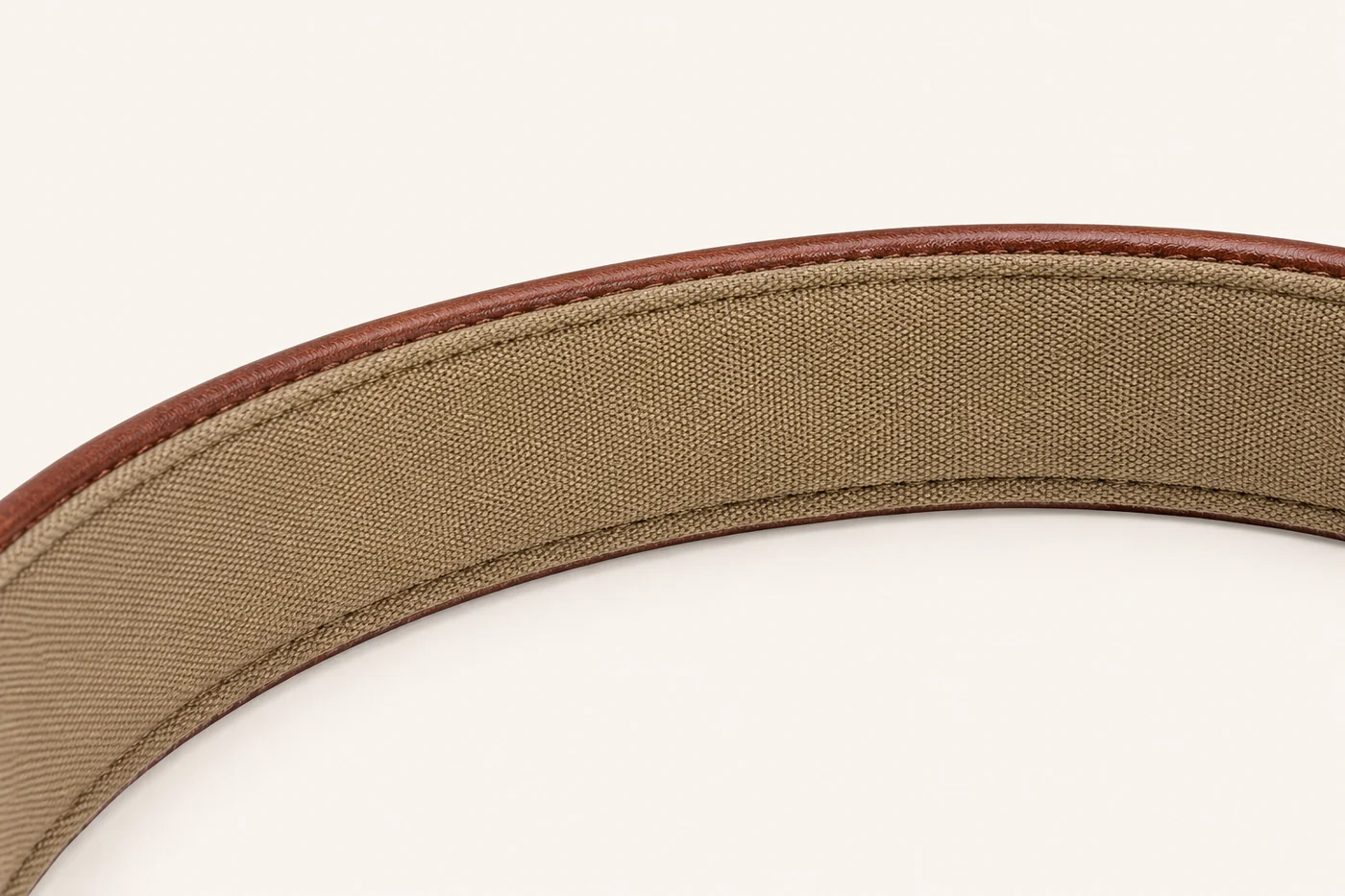 le collier courbé, face intérieure vers la caméra : la doublure taupe occupe le cadre, le cuir brun borde les deux tranches