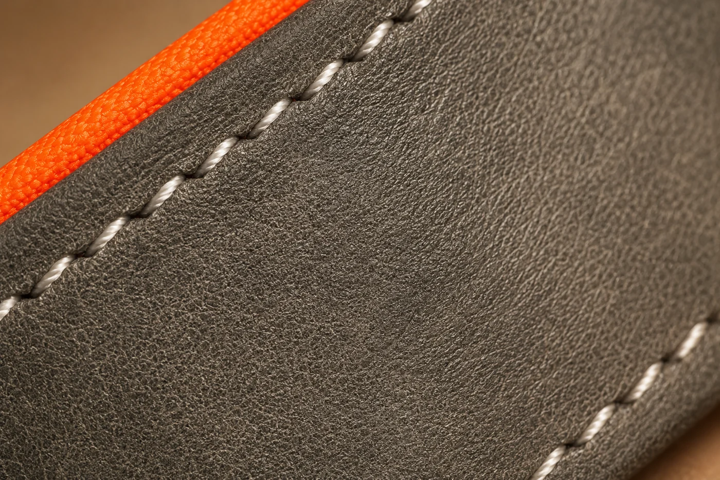 macro du grain du cuir gris, doublure orange visible sur la tranche