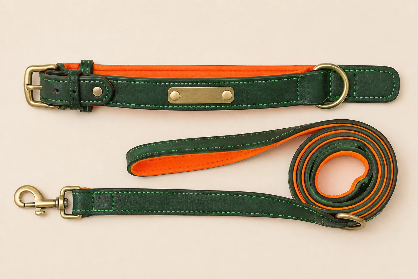 le collier et la laisse en cuir vert posés côte à côte, doublure orange visible sur la tranche des deux