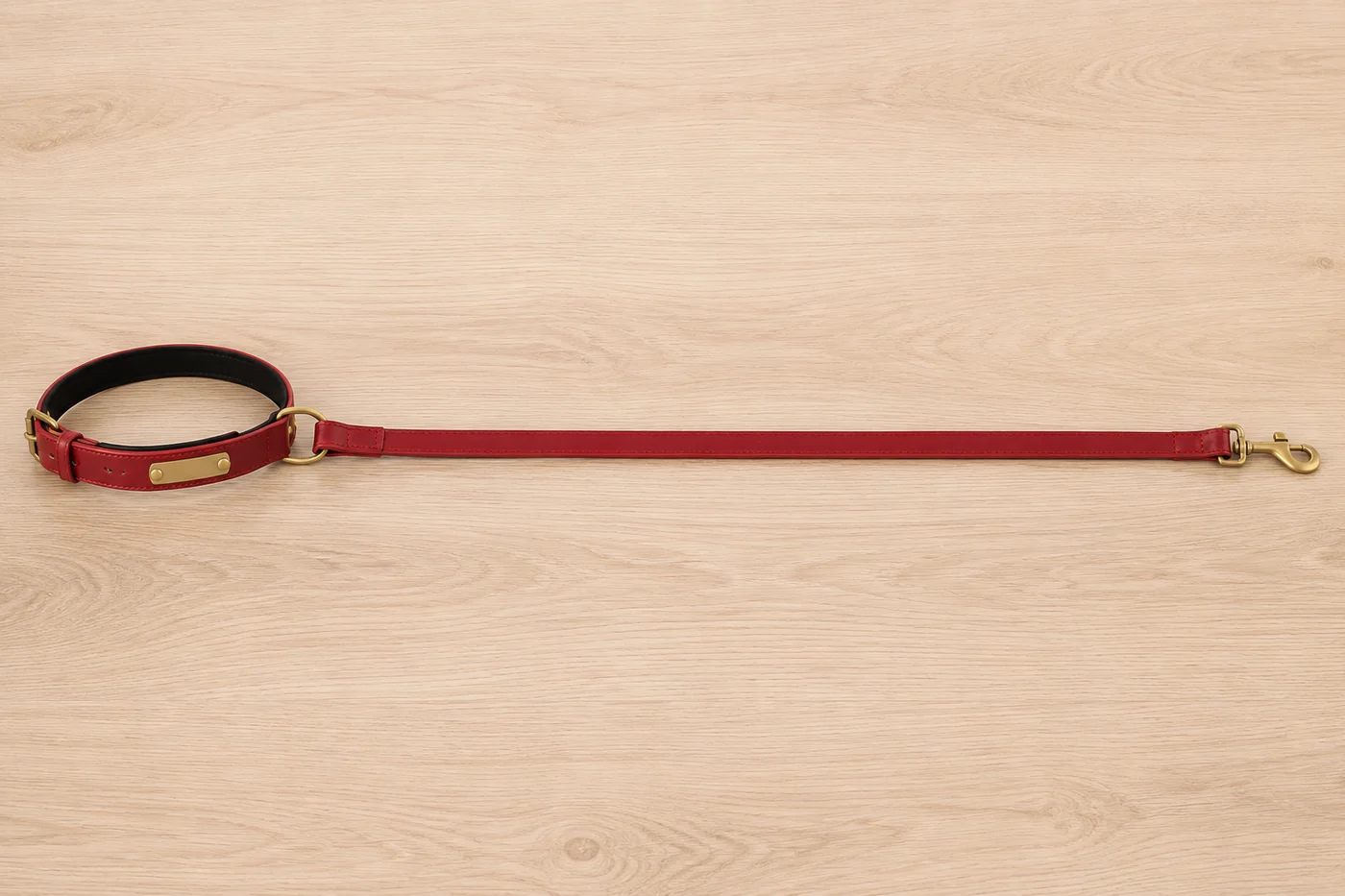 la laisse rouge déroulée à plat sur un plan de chêne clair, le collier rouge attaché à une extrémité